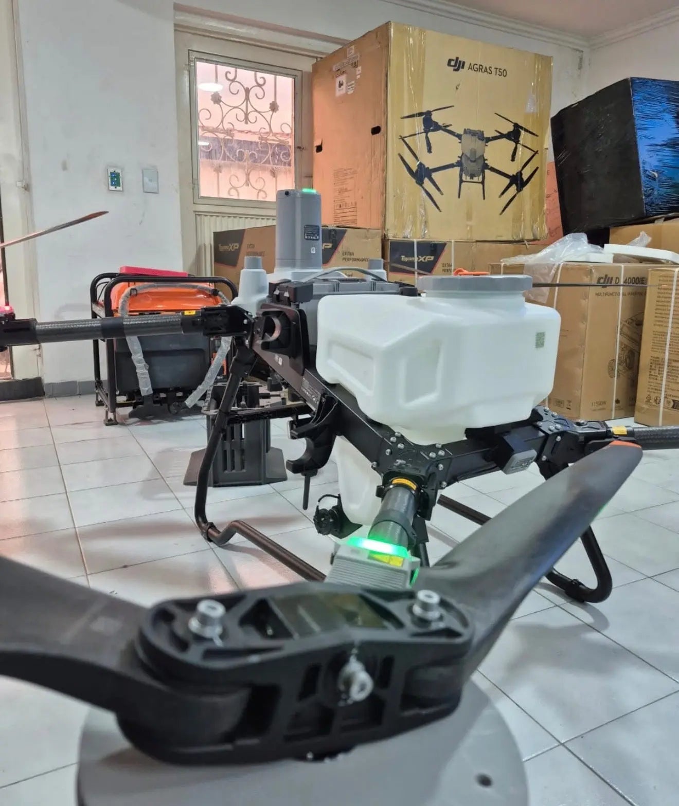 White agricultural sprayer drone with tank and landing legs, front close view