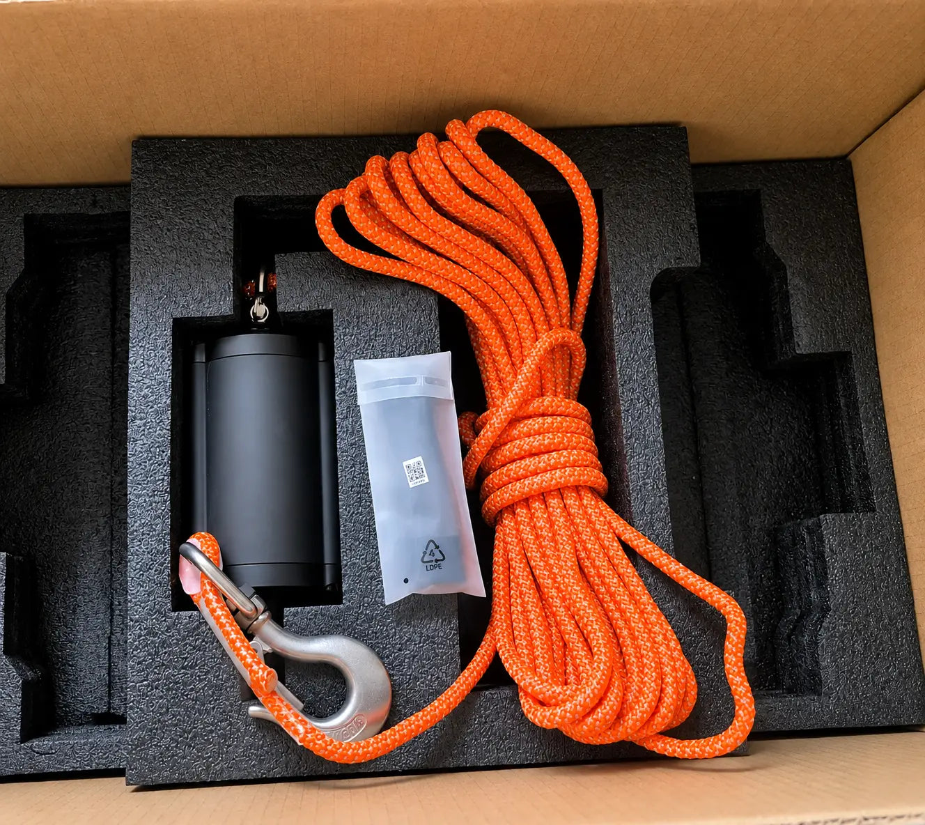 Black cylinder, hook, and orange braided cable set inside black foam tray