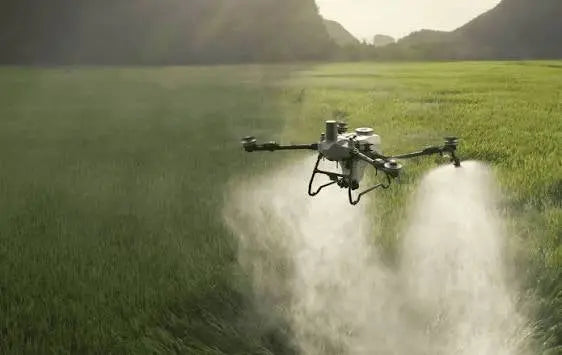 DJI Agras T55 agricultural sprayer drone spraying mist over green farmland