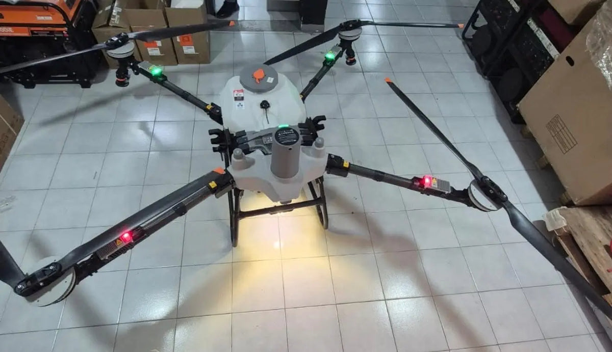 White agricultural sprayer drone with four arms and spray boom, front view