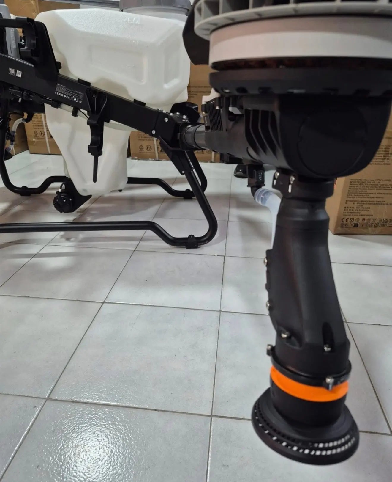 Close-up of white agricultural sprayer drone landing leg and orange-capped grip