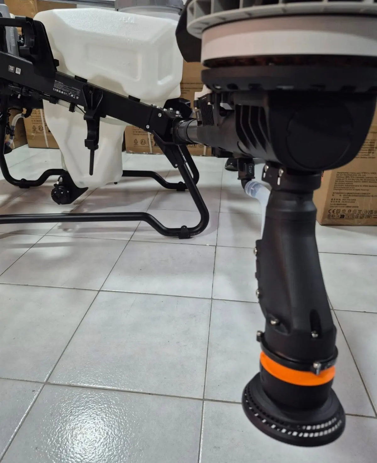 Close-up of white agricultural sprayer drone landing leg and orange-capped grip