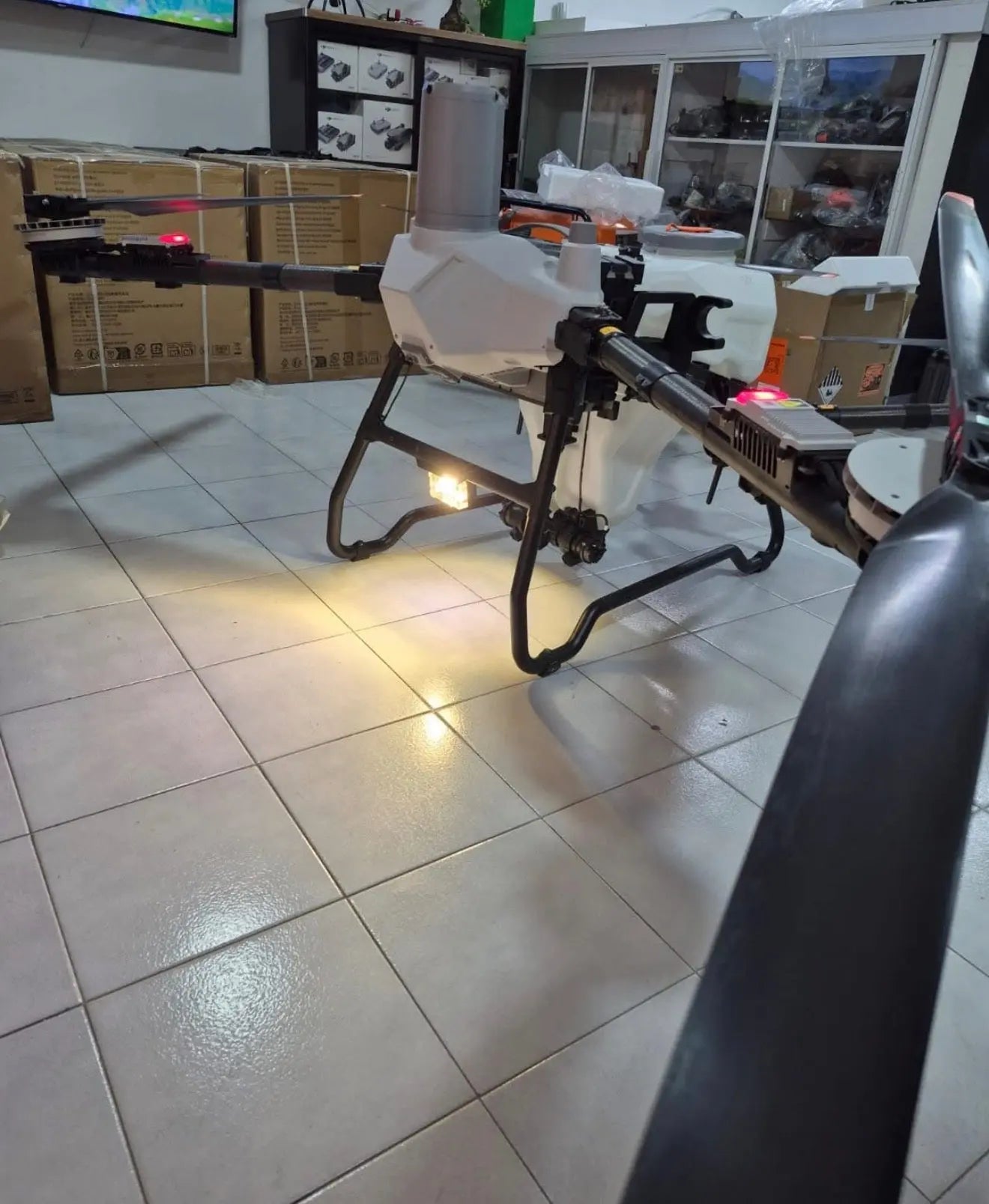 White agricultural sprayer drone on tripod stand with spray boom, side view