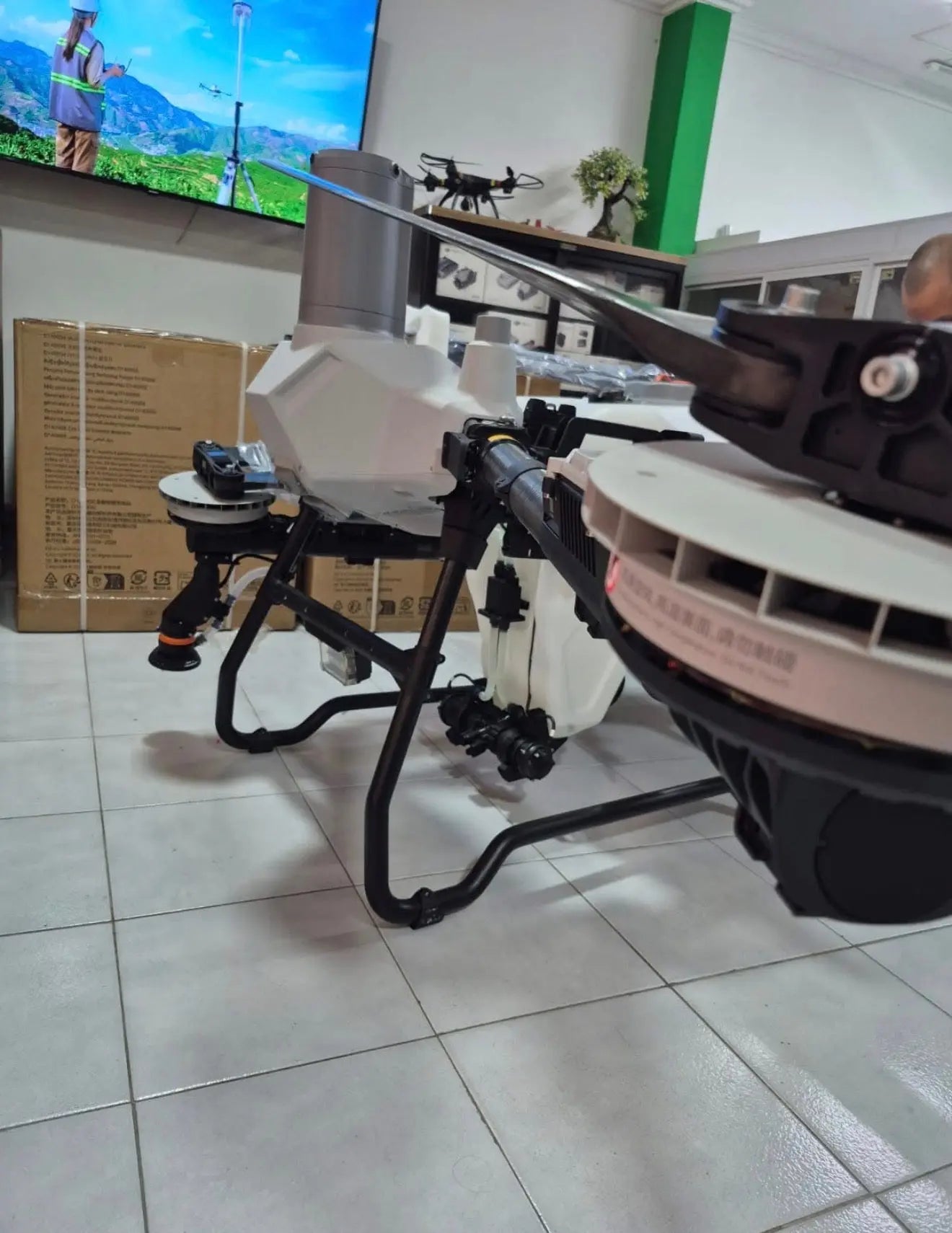 Close-up of white agricultural sprayer drone body, spray boom, and sensor housing