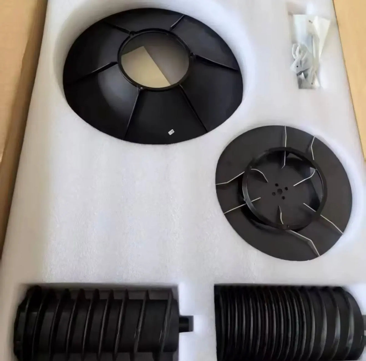 Black circular spreading system components with rotating disc and outlet openings on foam