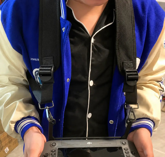 Remote controller worn with black DJI strap over jacket; metal clips and buckles visible