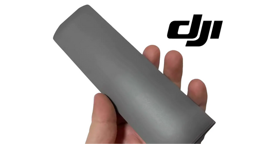 Dark gray cable cover plate held in hand, sleeve with open end.